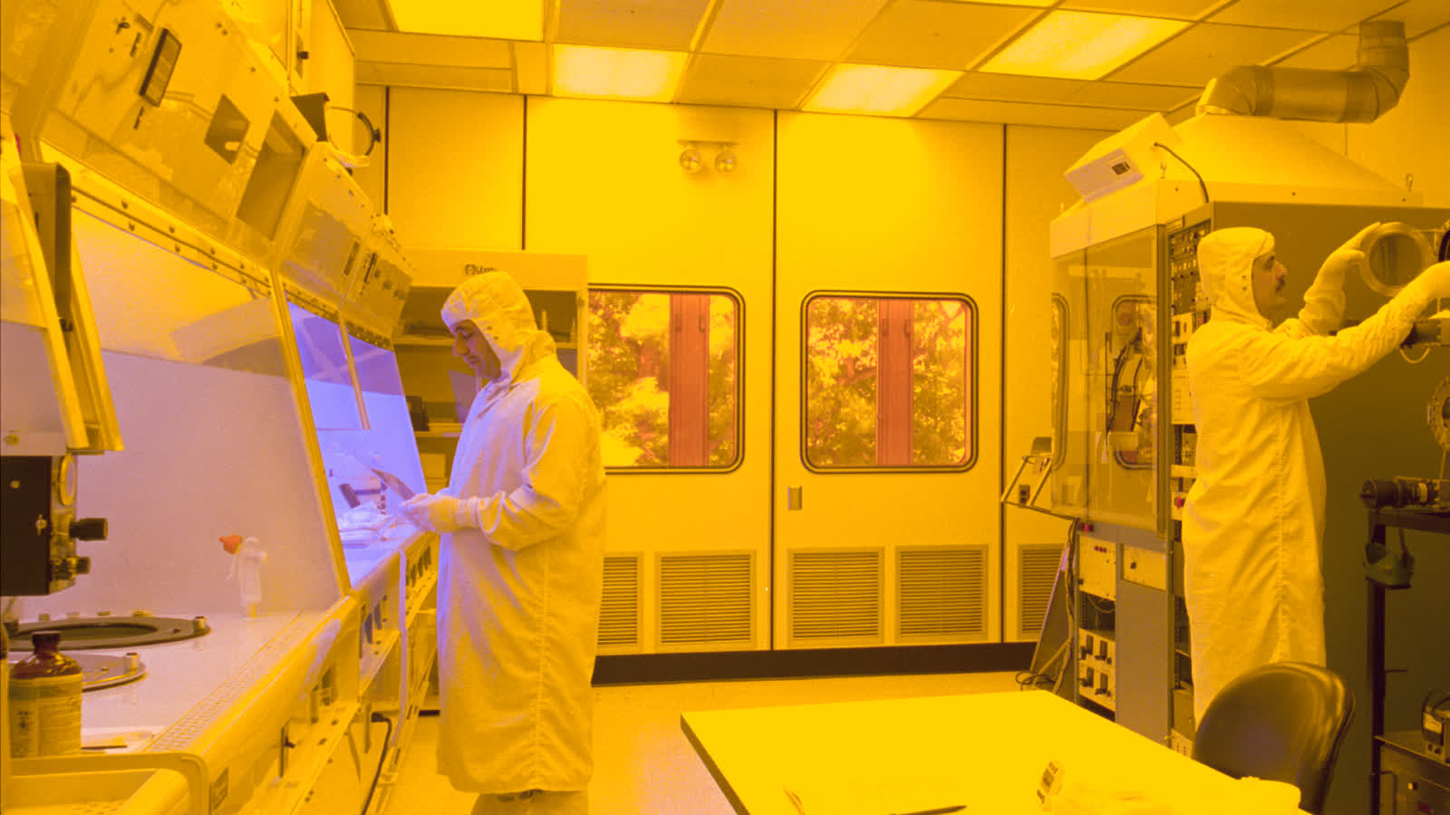Technicians working with process equipment in a semiconductor cleanroom