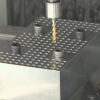 A synchronized tapping holder with a tap entering a test block in a machining center