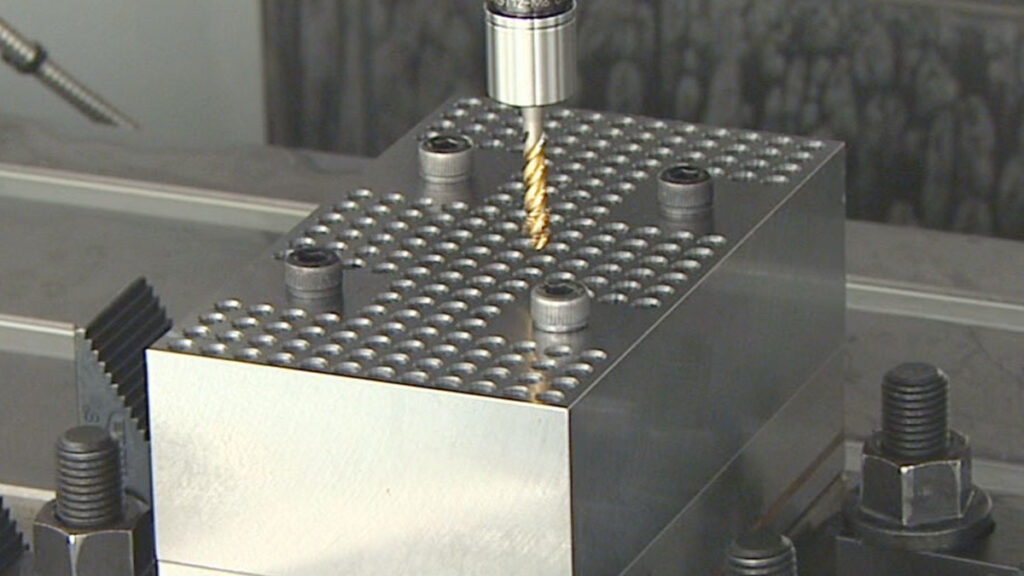 A synchronized tapping holder with a tap entering a test block in a machining center