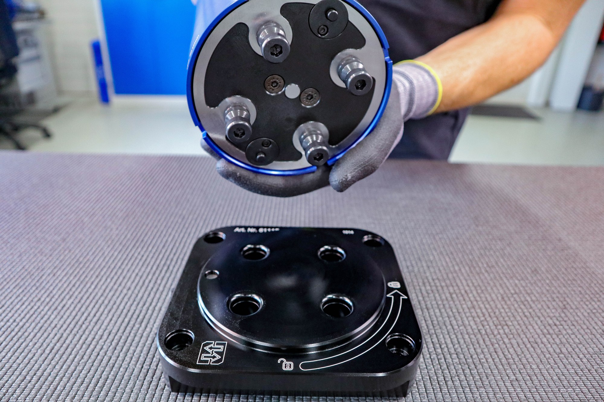 A fixture base with its clamping studs, about to be set into a bench-mounted station