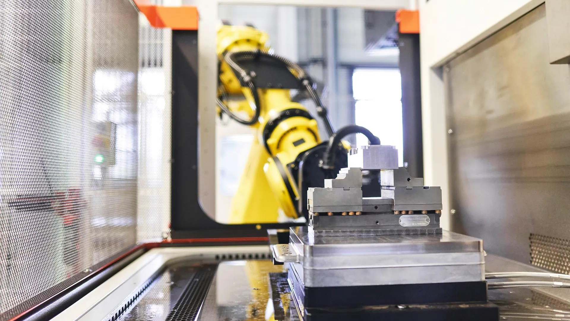 A robot and a pallet-mounted workpiece at a machine loading position