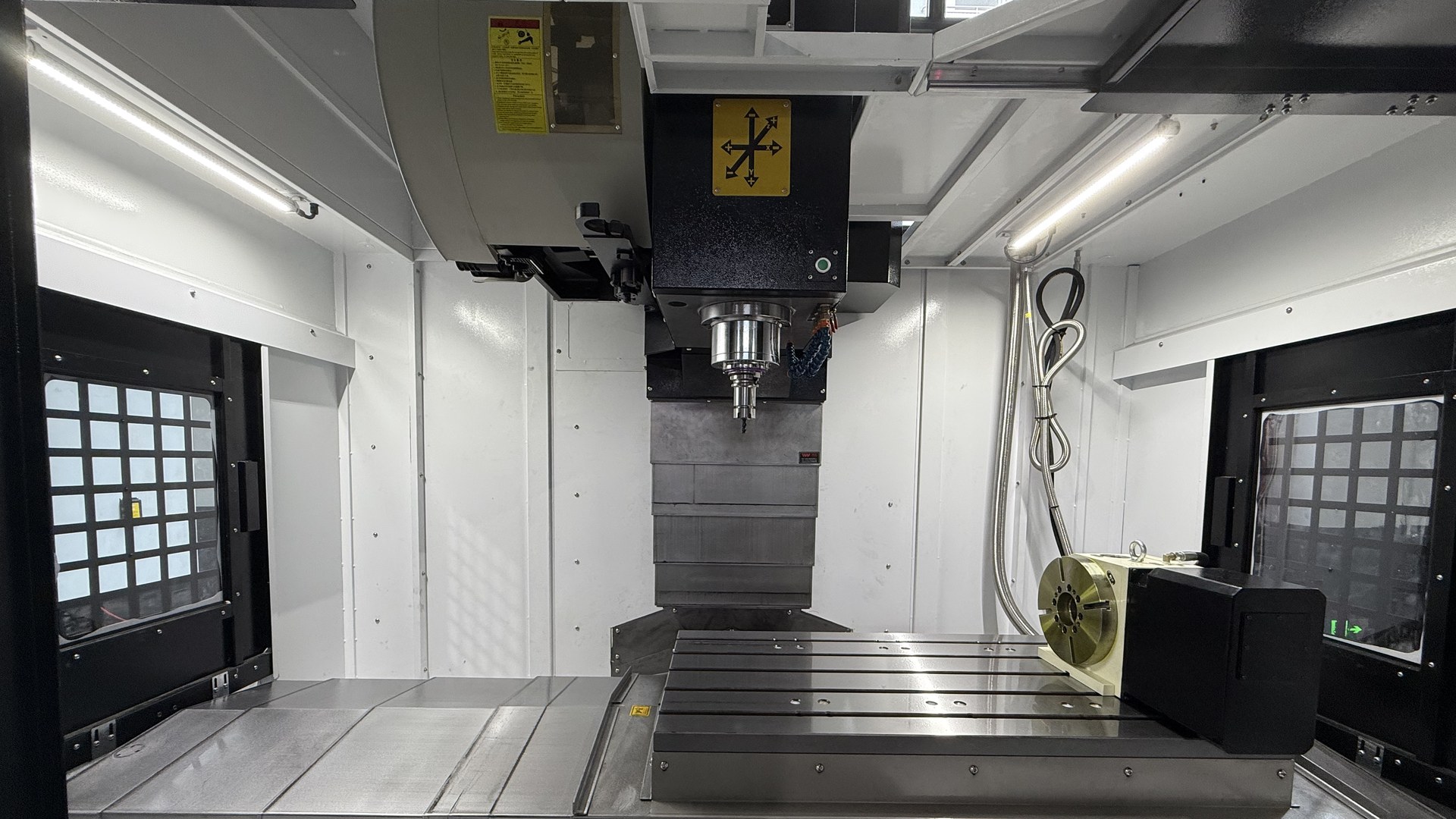 A 4th axis rotary table bolted to the right-hand end of a vertical machining center table, with the spindle above