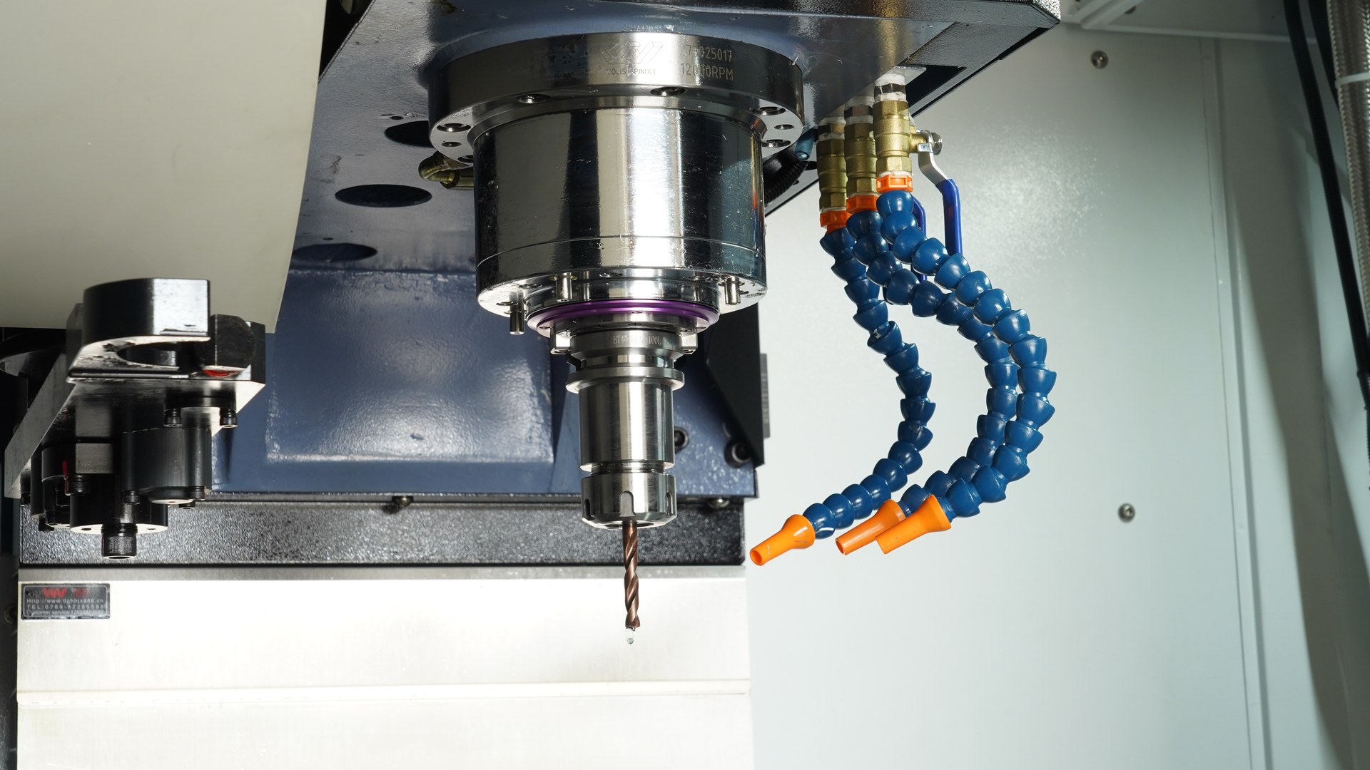 A drill held in the spindle of a CHANSIN CS-V855 vertical machining center, with coolant nozzles beside it